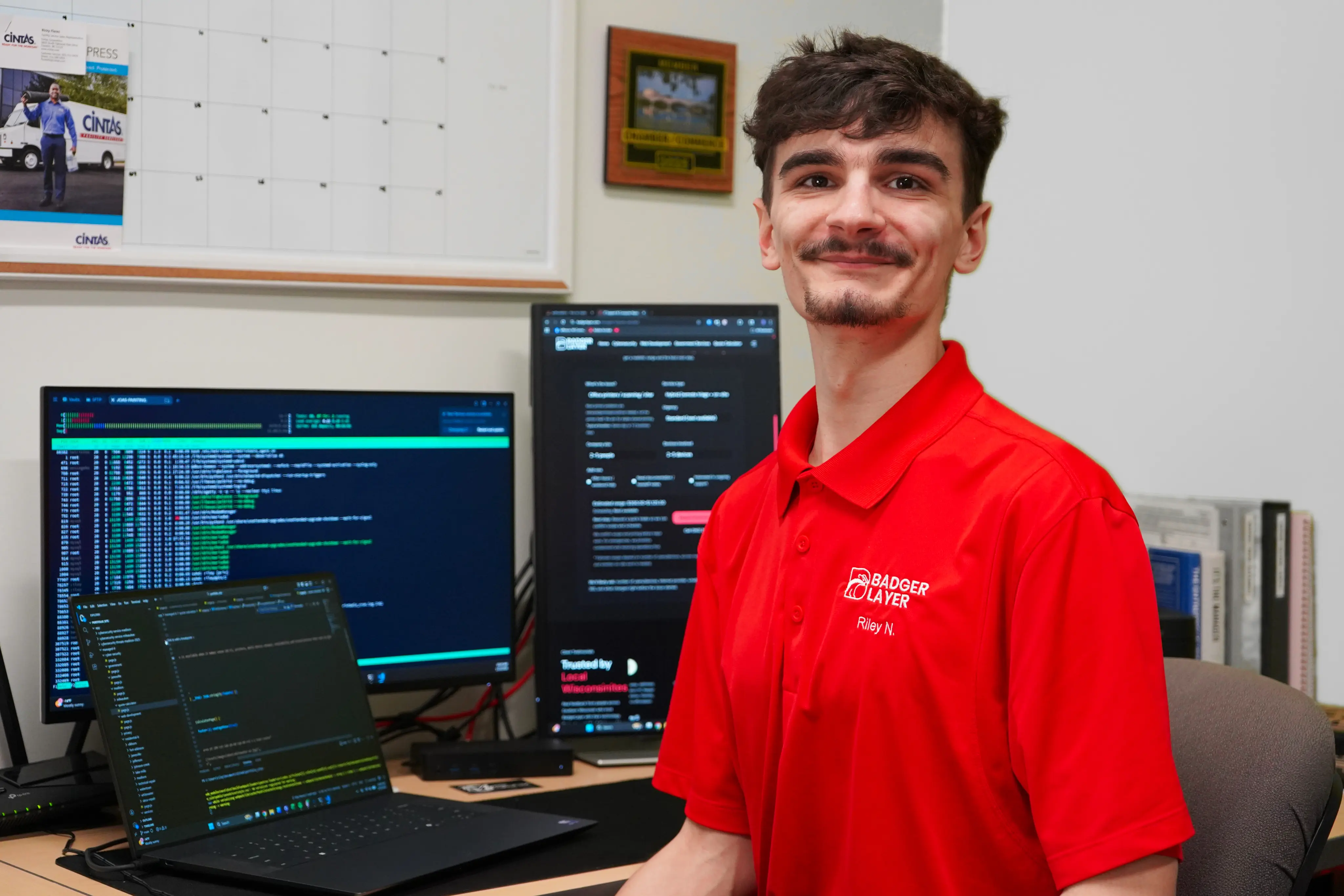 BadgerLayer technician at a workstation with monitoring and client systems on screen
